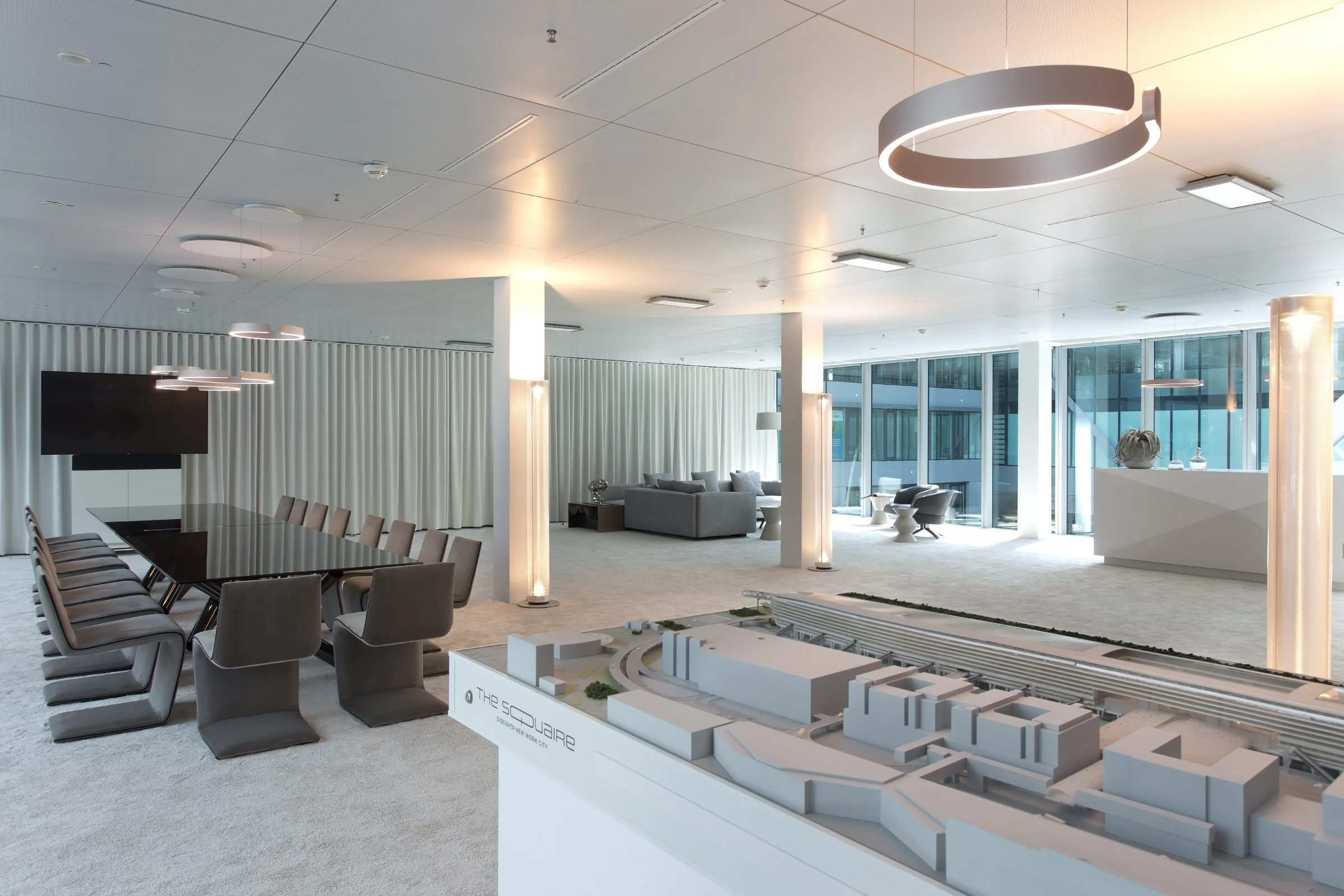 Light-filled Square Suite meeting area with a long conference table and reception desk