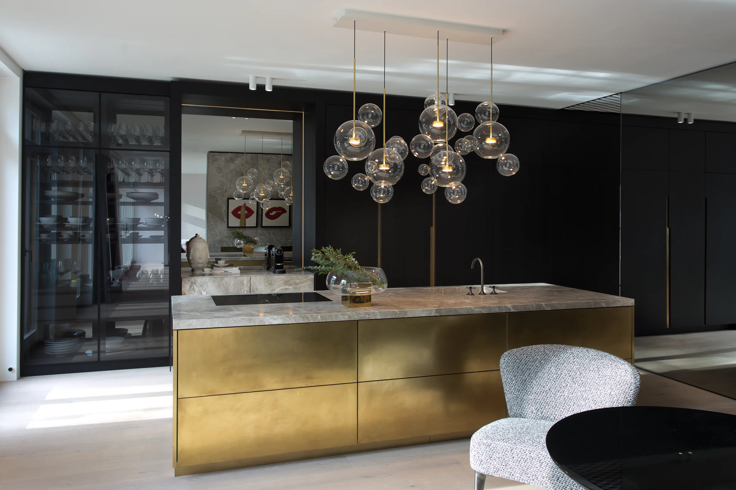 Casa Aurea kitchen with a brass island, dark cabinetry and sculptural glass lighting