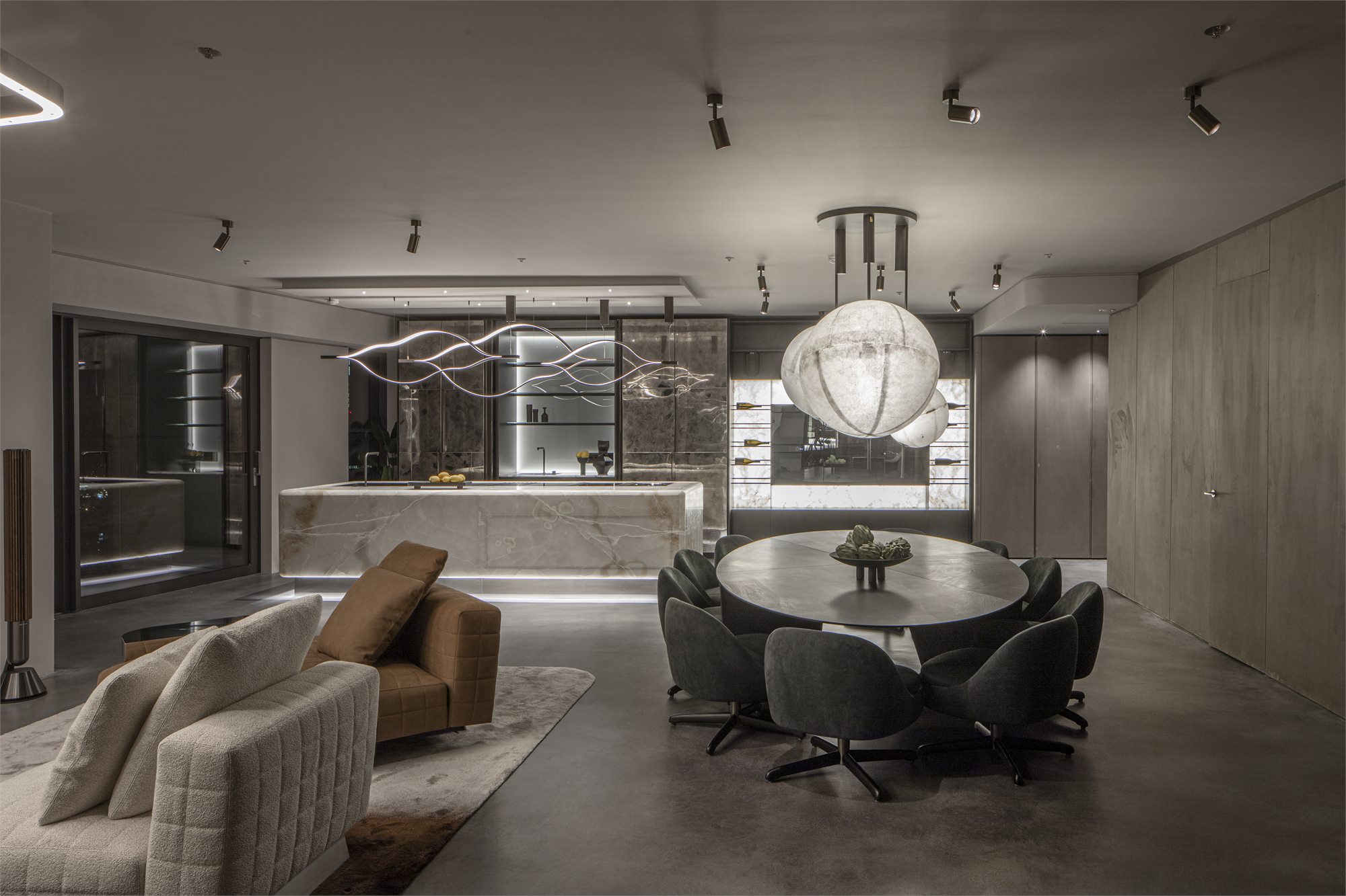 Open-plan living and dining area with an onyx kitchen island and sculptural lighting
