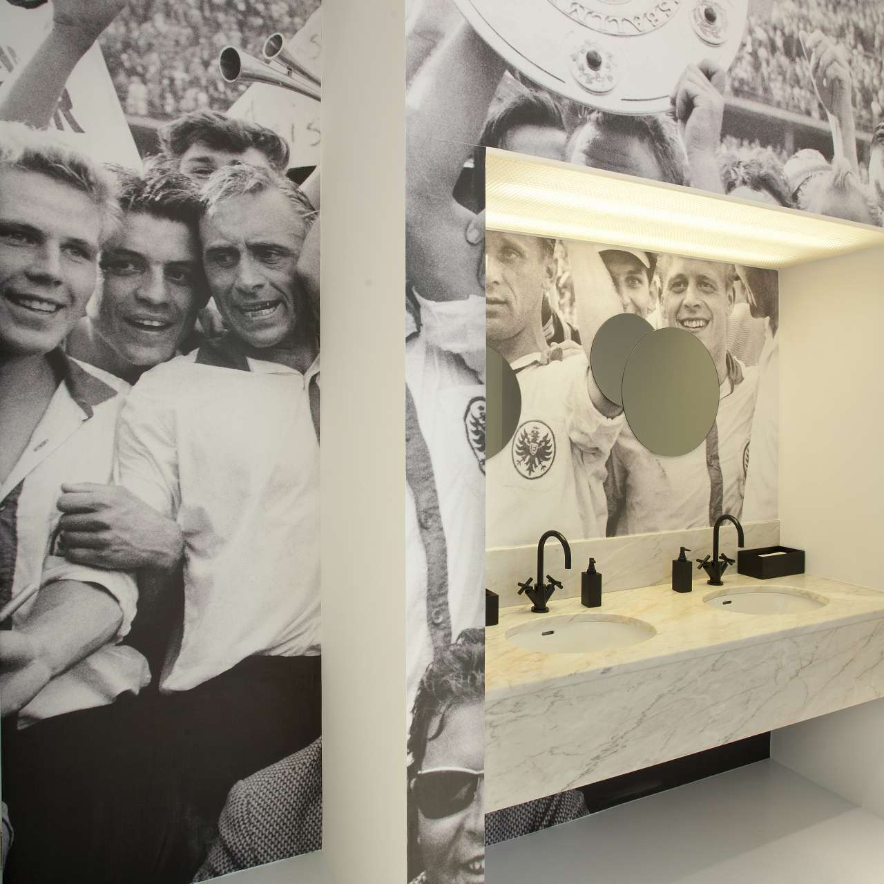 Washbasin at Main Palais set against a historic black-and-white photographic wall