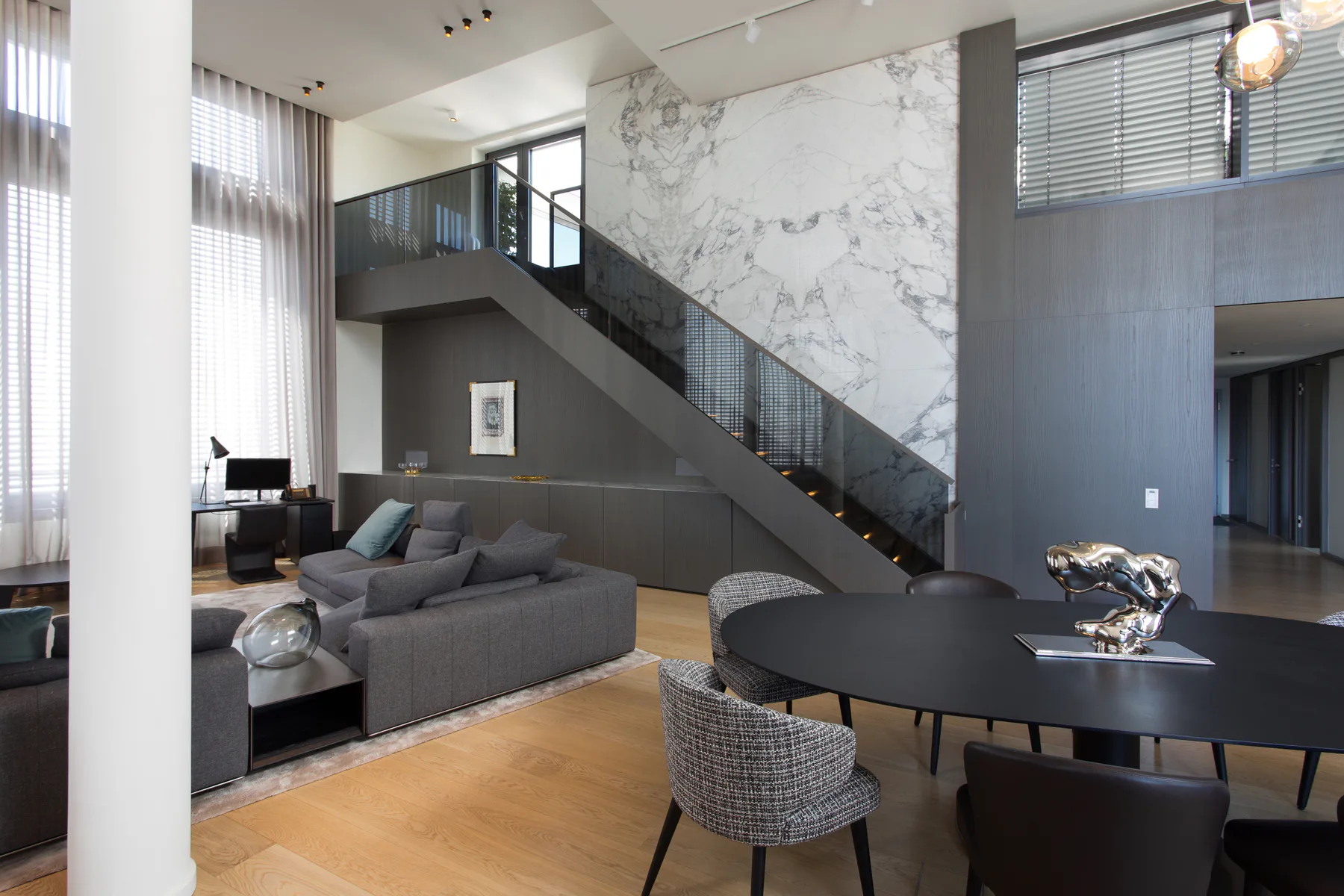 Light-filled living and dining area of the Maisonette Loft Apartment with staircase and marble wall