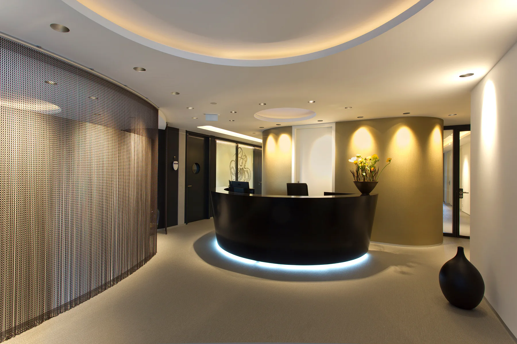 Reception of the Dental Practice Königstein with an oval desk, indirect lighting and gold-toned walls