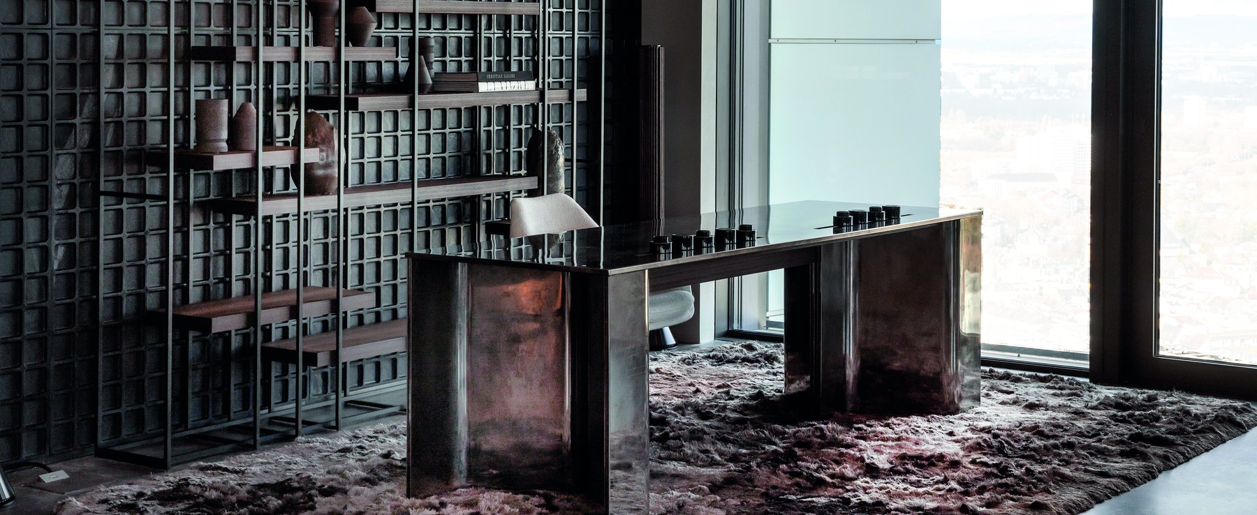 Interior with shelving wall, metal table and view over Frankfurt